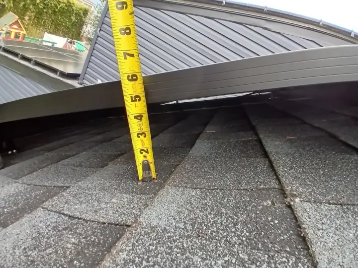 A tape measure checking panel height above shingles